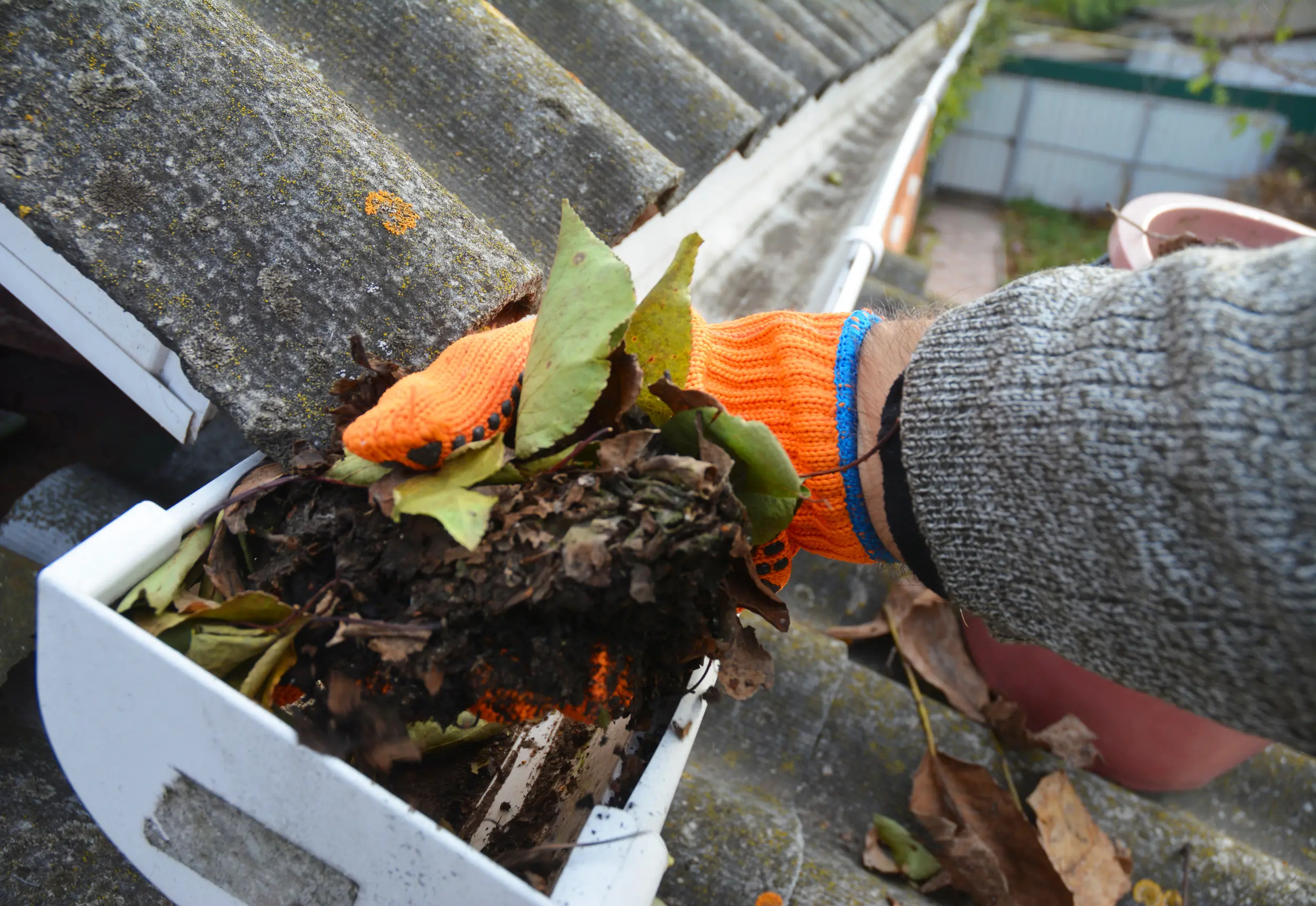 man cleaning leaves out of gutters