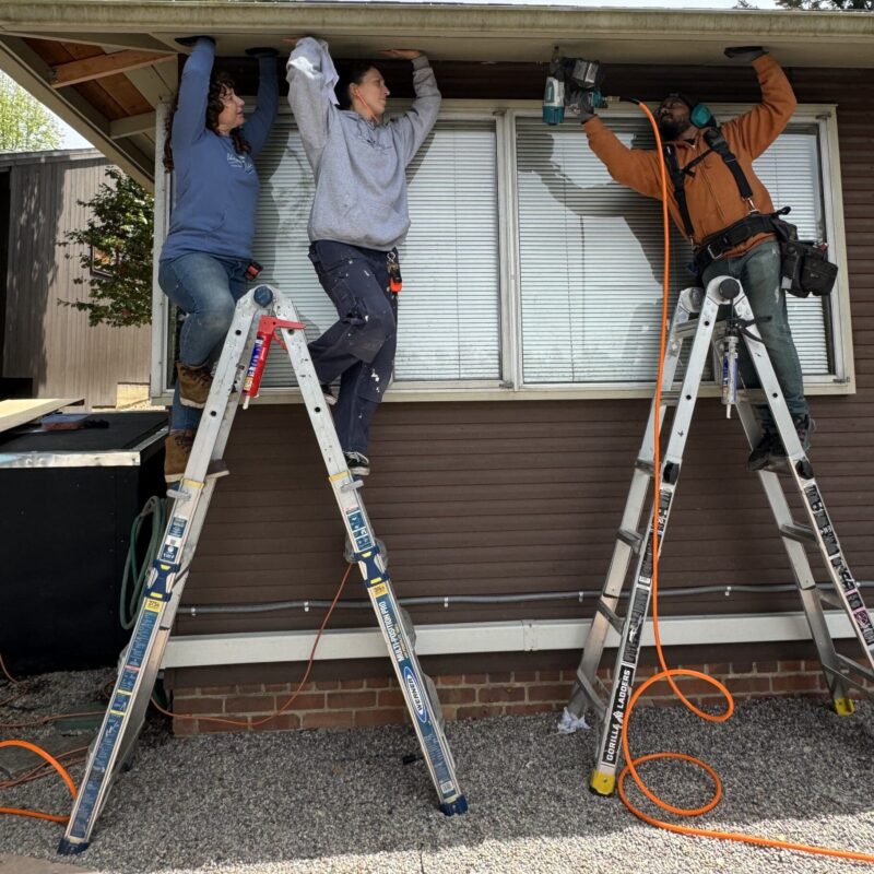 three people working on a house